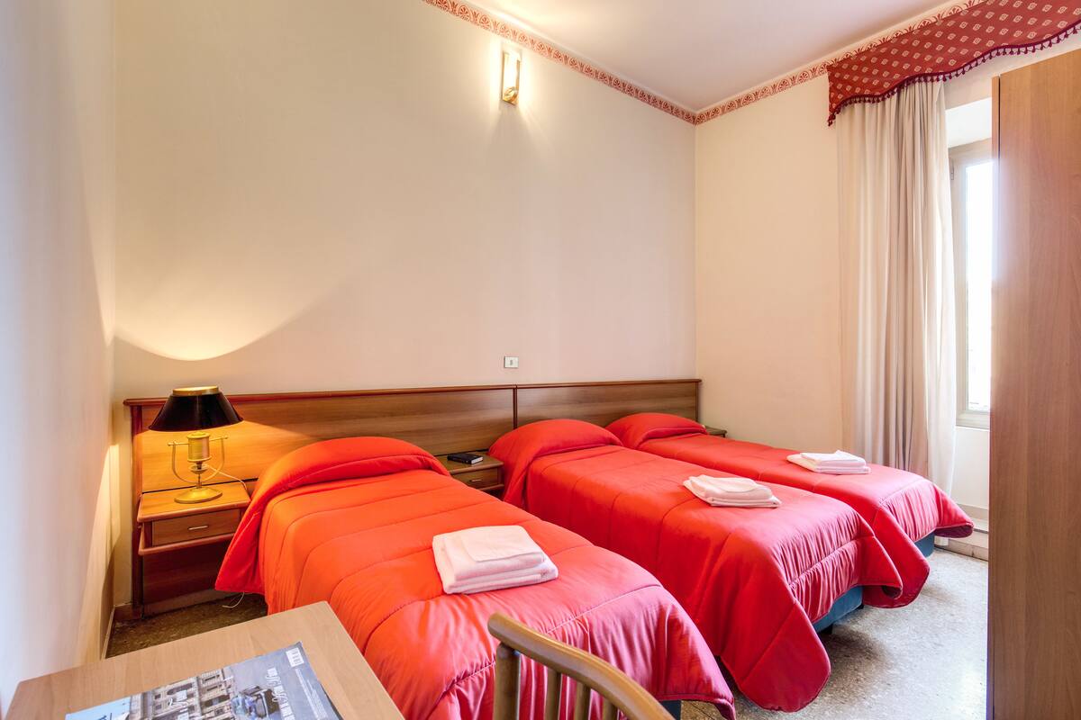 A hotel room with two beds, a nightstand with a lamp, and a wooden chair.