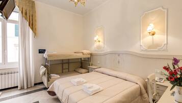 Une chambre d’hôtel avec un lit superposé, un bureau avec un téléphone, un vase de fleurs et des lampes fixées au mur.