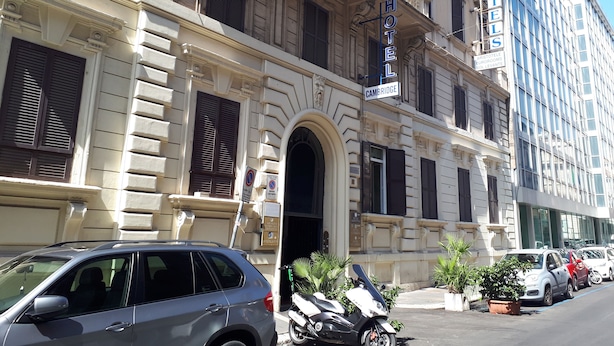 A historic building with a prominent entrance, a sign indicating it is a hotel, and a modern building adjacent to it. - Hotel Cambridge (Rome)