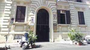 A historic building with a prominent entrance, multiple balconies with potted plants, and a flag. - Hotel Cambridge (Rome)