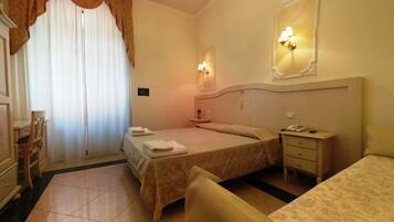 Ein Hotelzimmer mit Bett, Nachttisch, Sessel und Schreibtisch mit Stuhl.