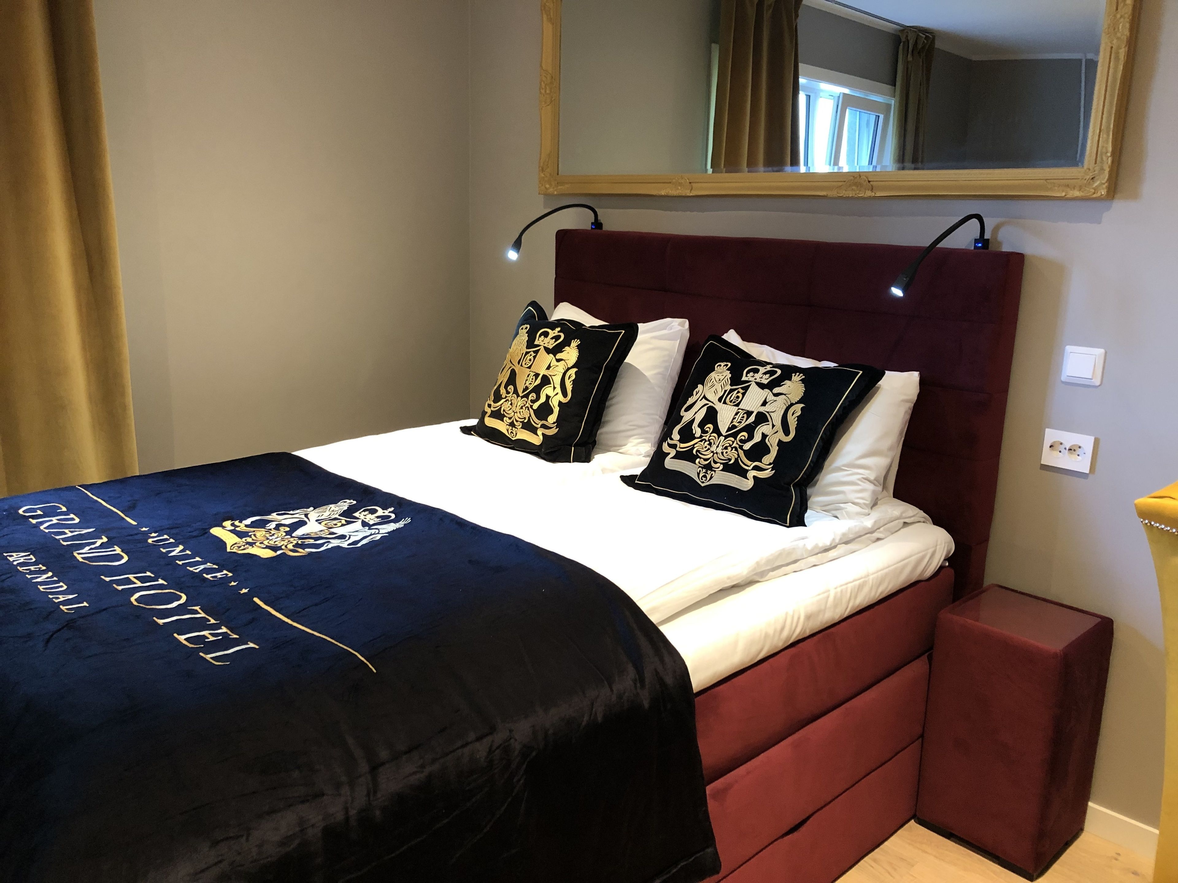 A hotel room with a bed, a mirror, and a nightstand.