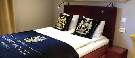 A hotel room with a bed, a mirror, and a nightstand.