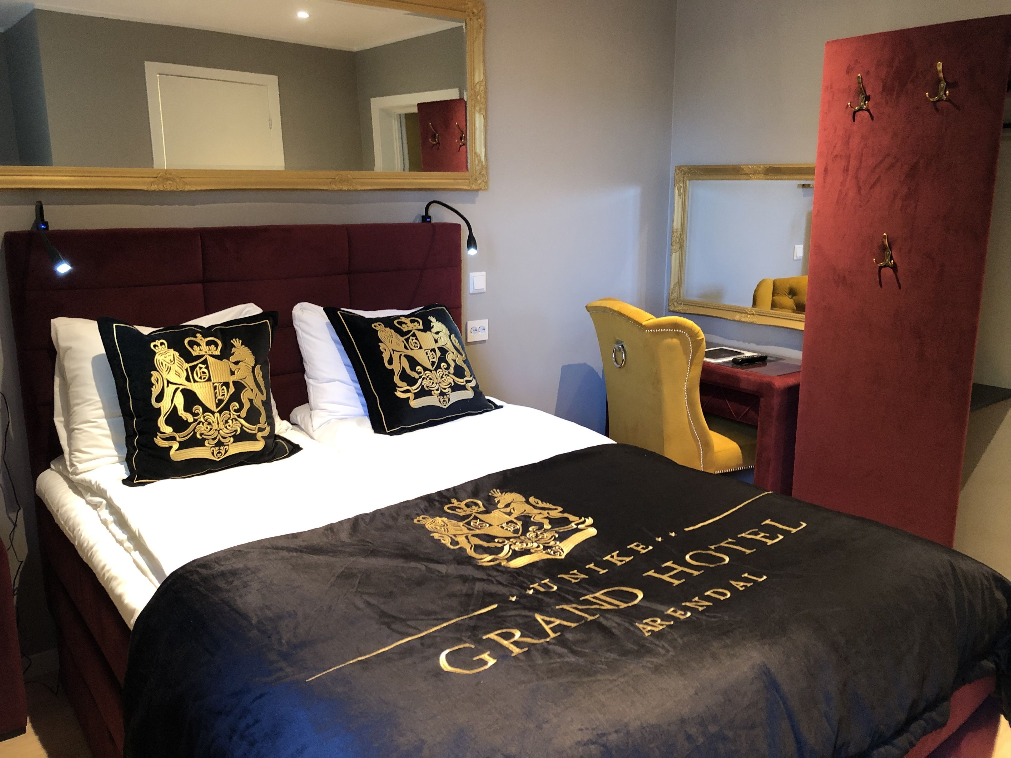 A hotel room with a bed, a desk, a chair, and a wardrobe.