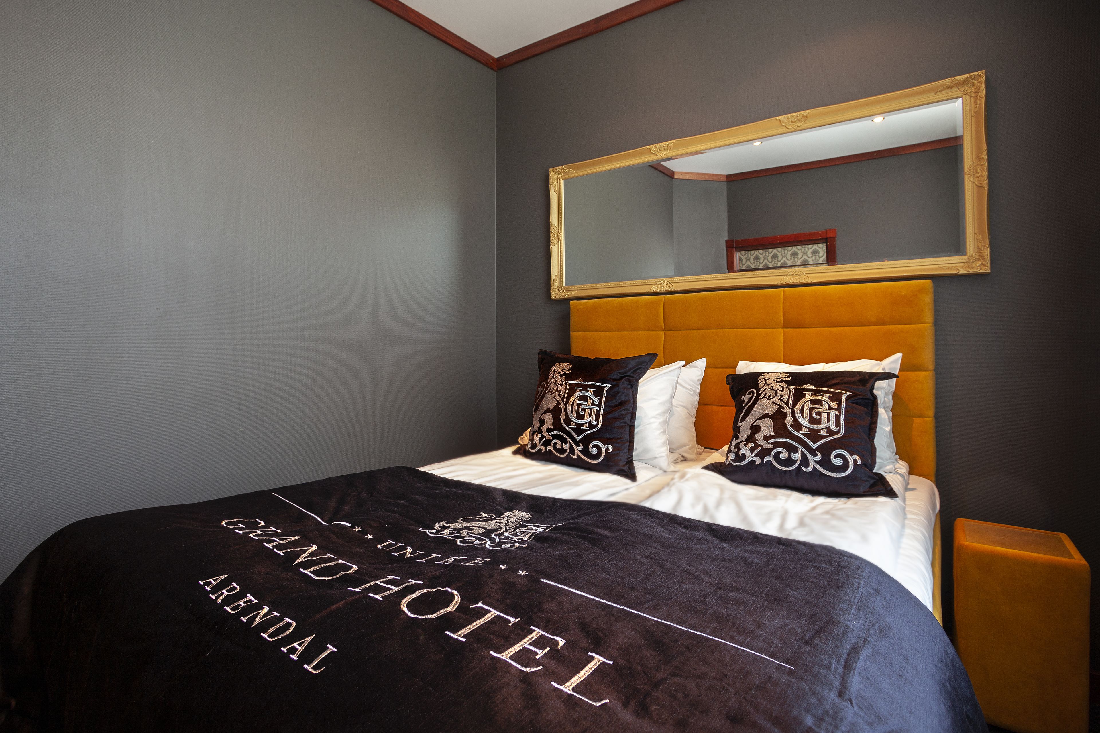 A hotel room with a bed, a large mirror, and a headboard.