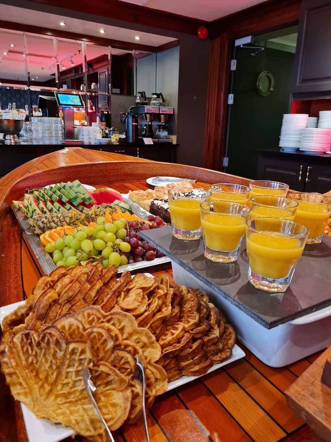 A buffet with waffles, fruits, and orange juice.
