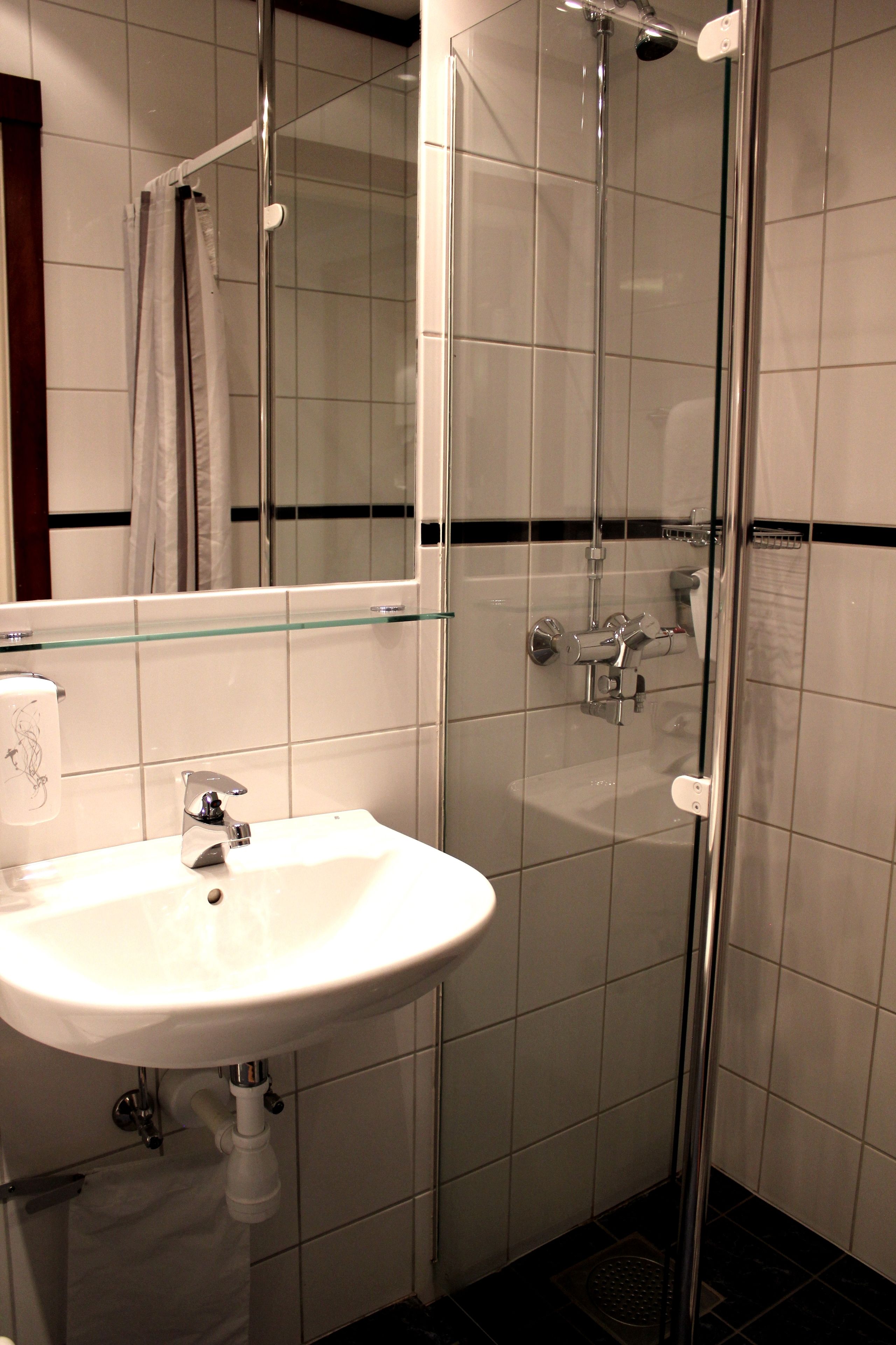 A bathroom with a glass shower enclosure, a white sink, and a mirror above the sink.