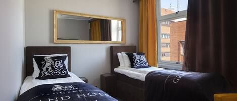 A hotel room with two beds, a large mirror, and a window with curtains.