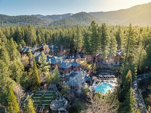 A resort with multiple buildings, a swimming pool, and a mountainous backdrop.
