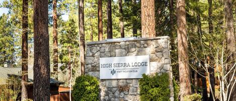 A stone sign with 'High Sierra Lodge' and 'Hyatt Vacation Club' text, surrounded by tall trees.