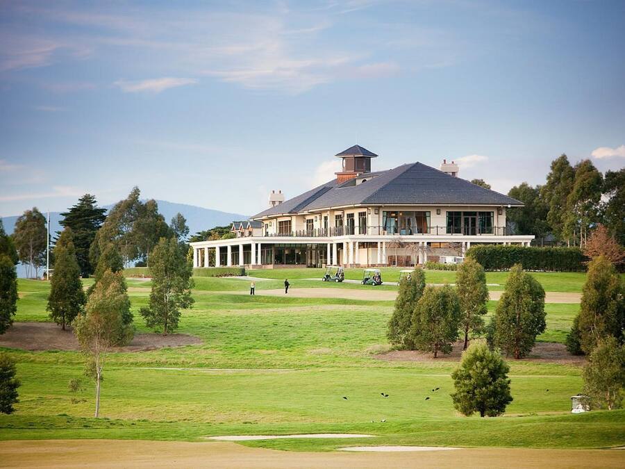 A large, multi-story building with a symmetrical facade, surrounded by a well-maintained lawn and trees.