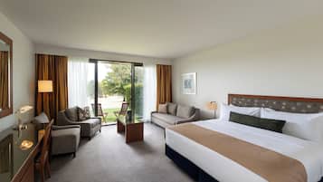 A hotel room with a bed, two sofas, a desk, and a chair.