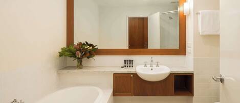 A bathroom with a bathtub, a sink, and a toilet. There is a wooden vanity with a mirror above the sink.