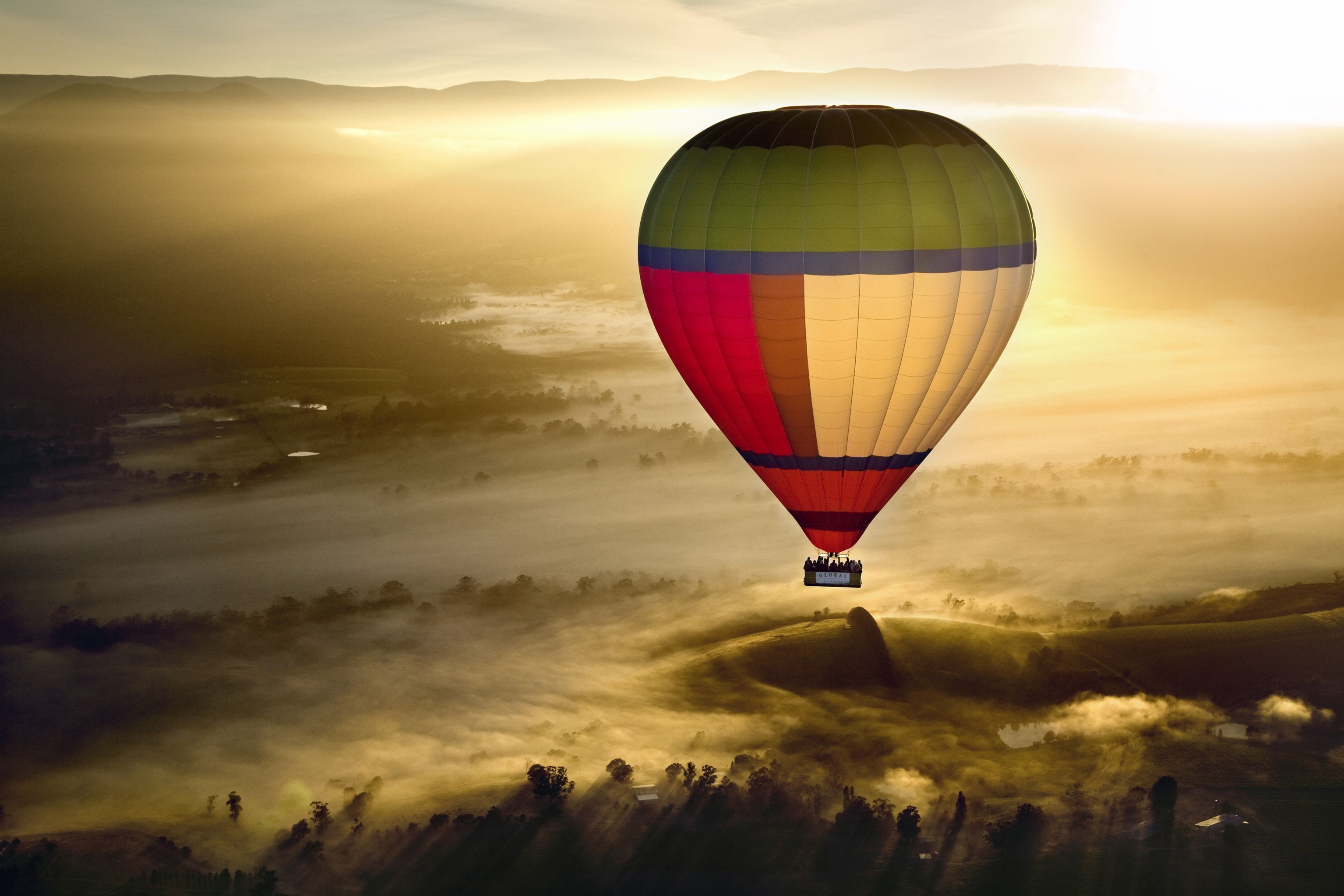A hot air balloon over a misty landscape with rolling hills.