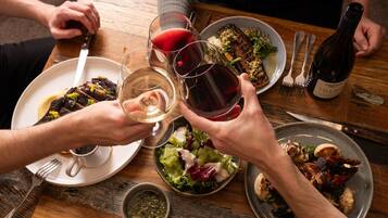 A dining table with plates of food, glasses of wine, and a bottle of wine.