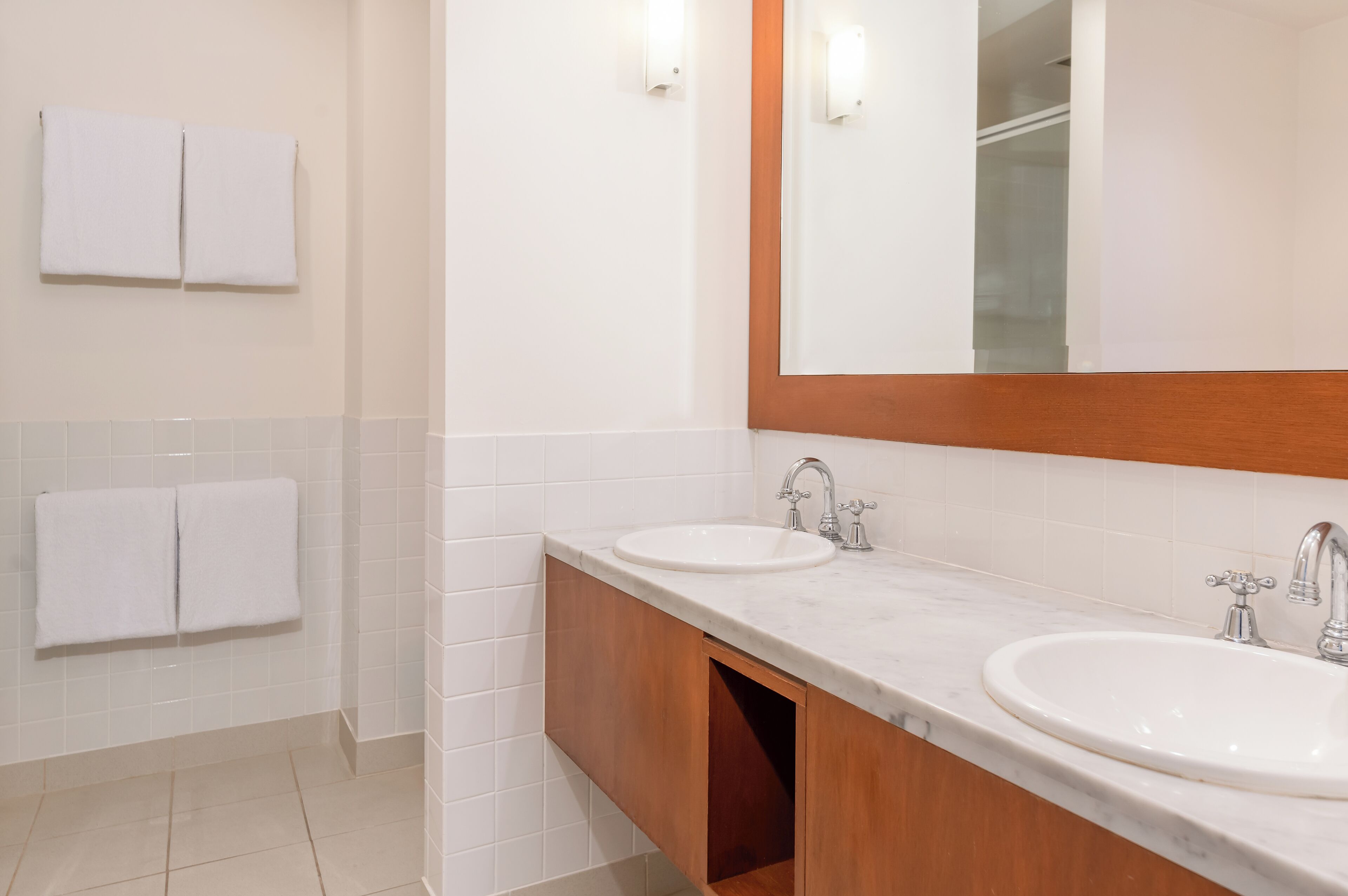 A bathroom with two sinks, a mirror, and two towels hanging on the wall.