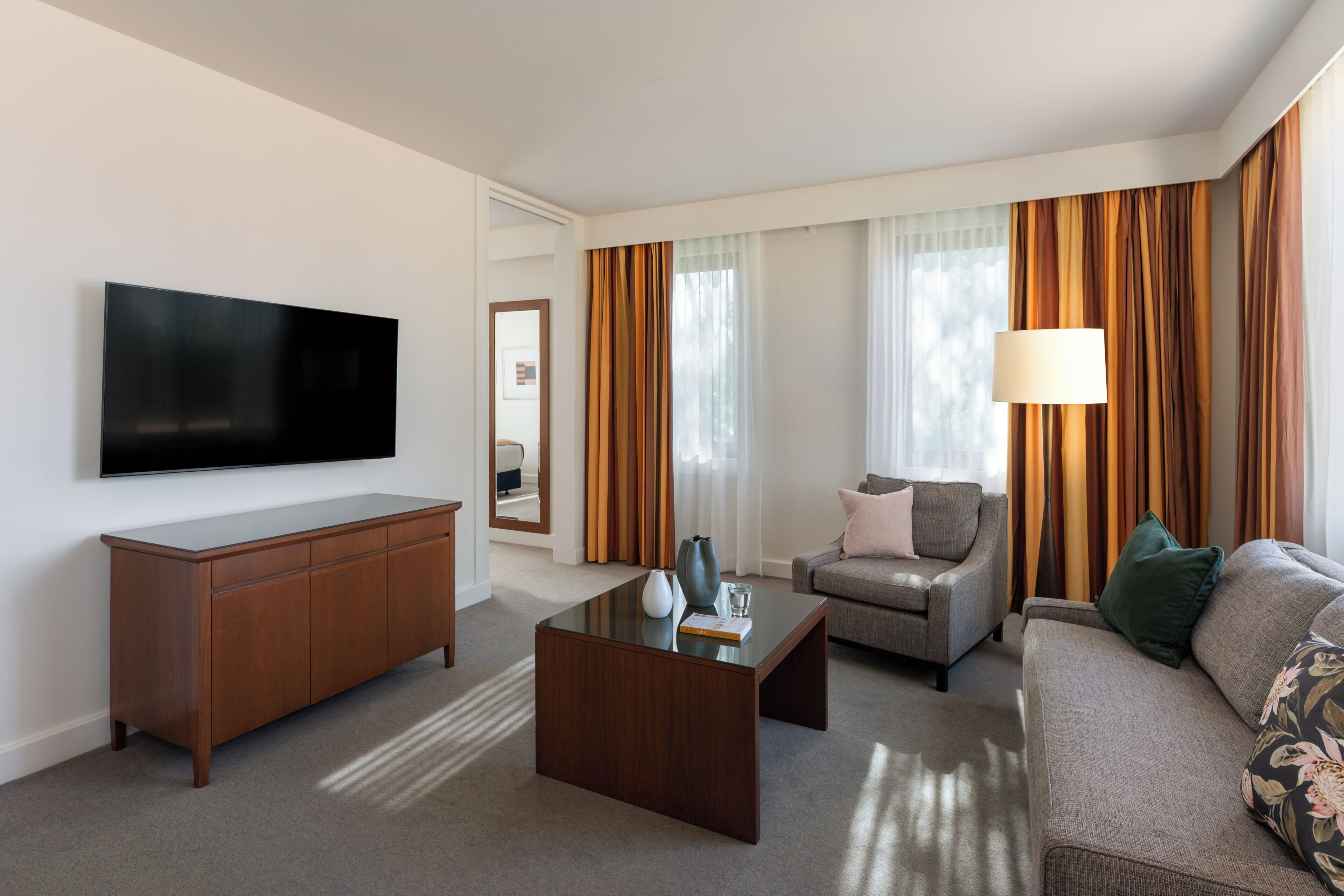 A modern living room with a flat-screen TV, a wooden coffee table, a sofa, a chair, and a lamp.