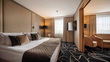 Una habitación de hotel con una cama grande, dos sillones, un televisor y un escritorio.