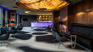Un espace bar moderne doté d’un design de plafond original, d’un agencement des sièges soigné et d’un comptoir de bar.