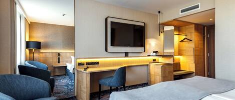 Habitación de hotel con cama, escritorio, silla, televisor, armario y baño.
