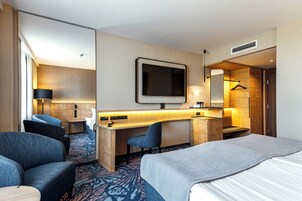 Une chambre d’hôtel équipée d’un lit, d’un bureau, d’une chaise, d’une télévision, d’une armoire et d’une salle de bain.