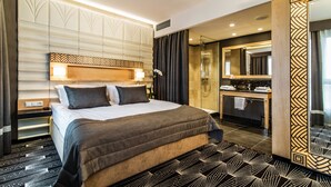 Une chambre d’hôtel moderne dotée d’un grand lit, d’une salle de bain avec douche et d’une coiffeuse avec miroir.