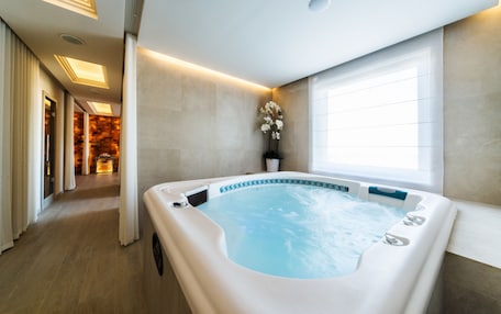A modern bathroom with a large bathtub, a potted plant, and a window providing natural light.