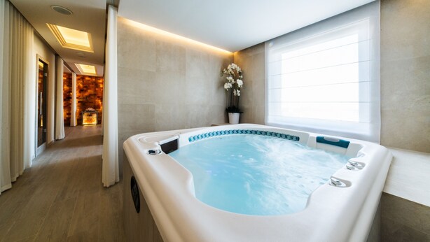 Une salle de bain moderne avec une grande baignoire, une plante en pot et une fenêtre laissant entrer la lumière naturelle.