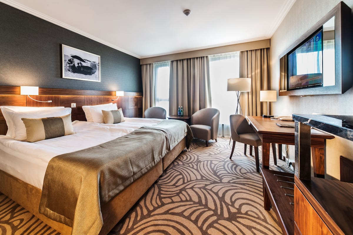 Een hotelkamer met een groot bed, een bureau, een stoel en een televisie.