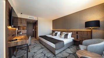 Ein modernes Hotelzimmer mit einem großen Bett, einem Schreibtisch, einem Sessel und einer Lampe.