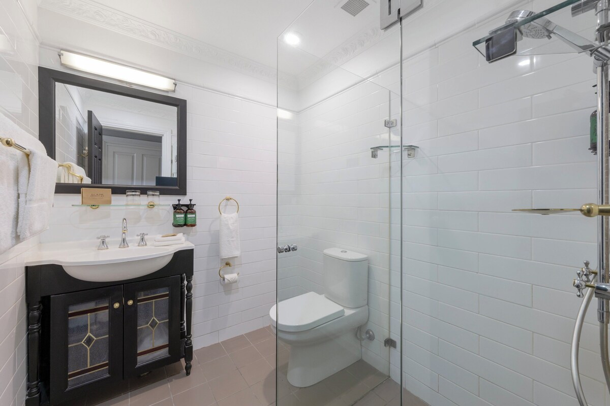 A modern bathroom with a glass-enclosed shower, a white sink with a vanity, and a large mirror.