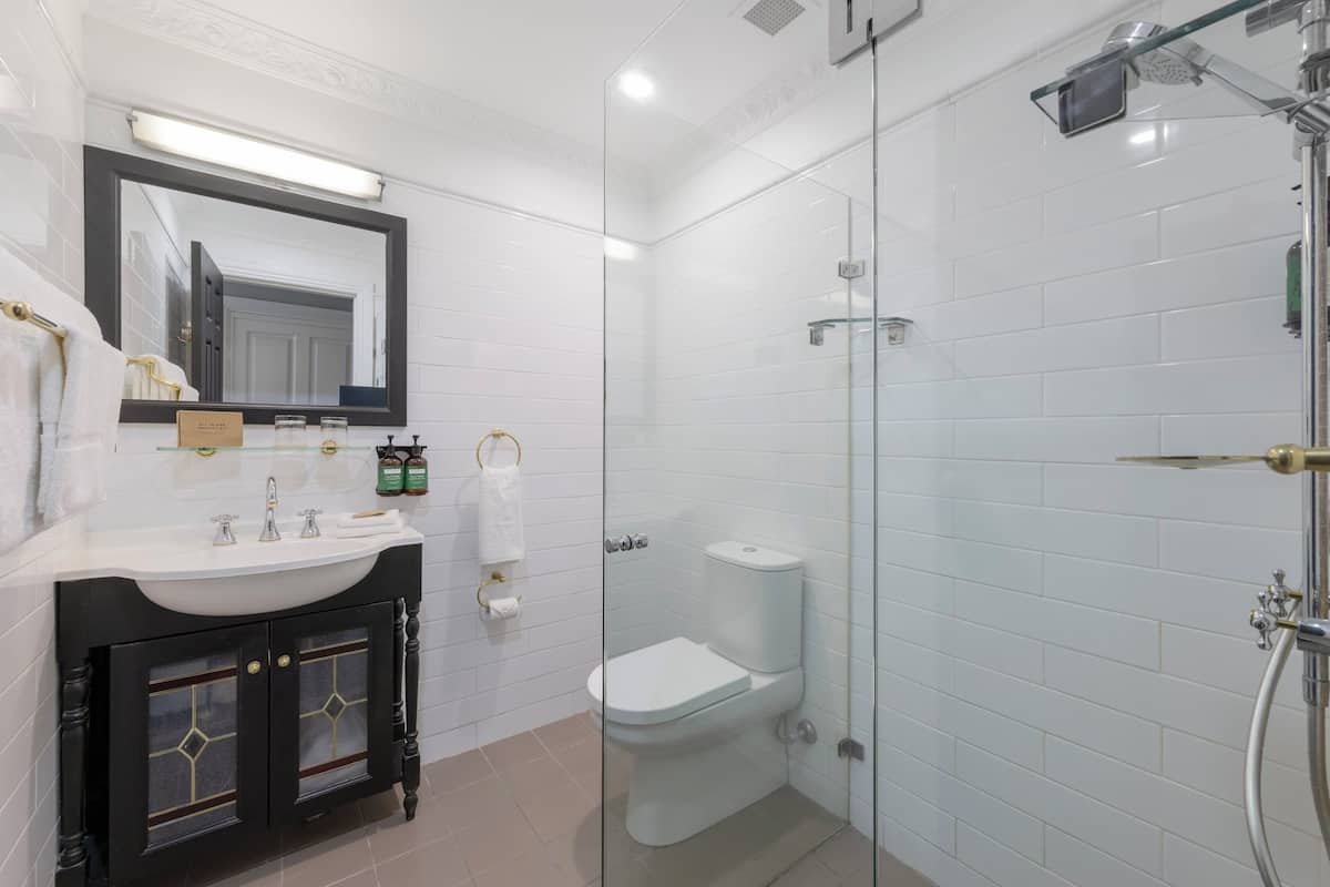 Et moderne badeværelse med en glasafskærmet bruseniche, en hvid vask med underskab og et stort spejl.