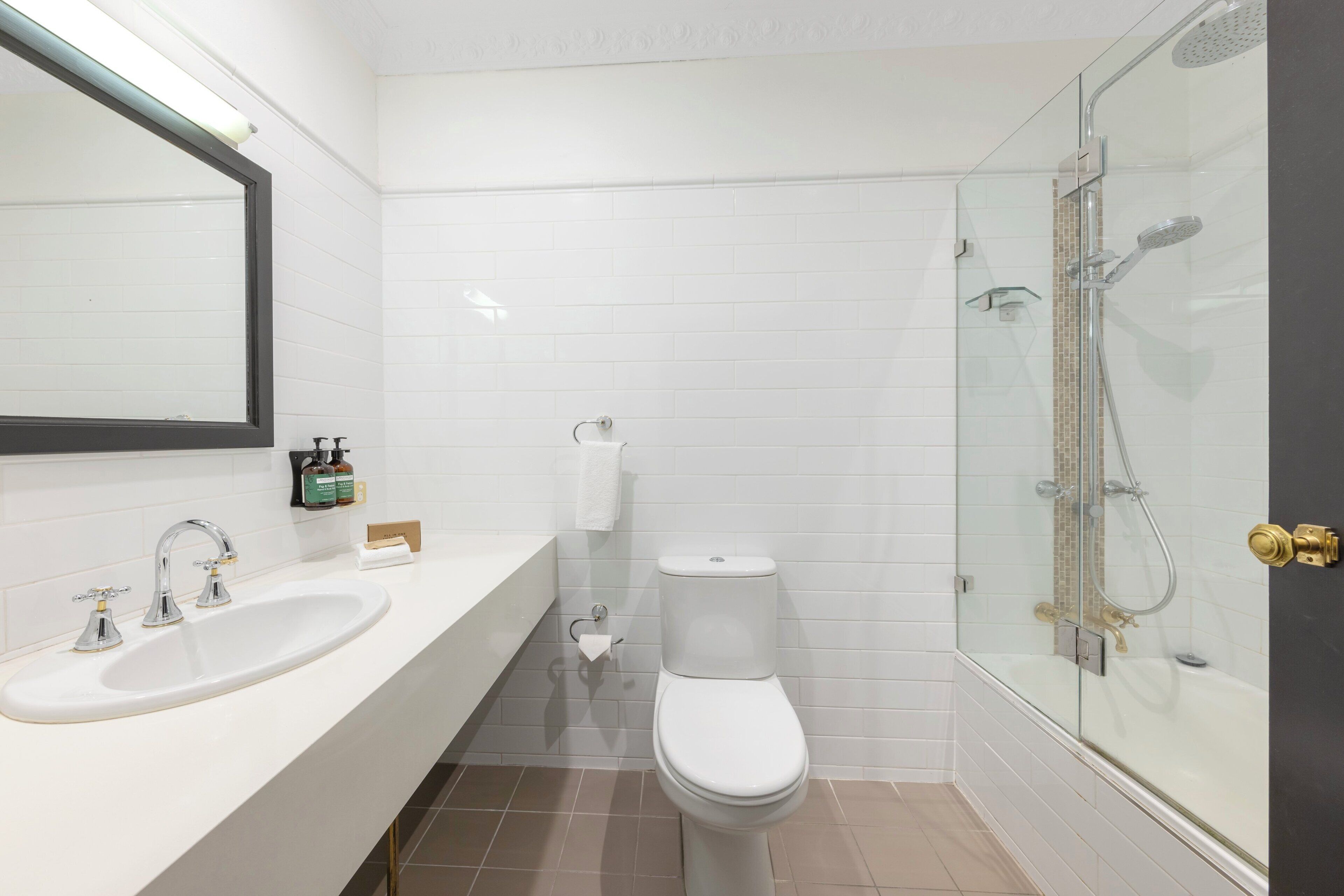 A modern bathroom with a white sink, toilet, and glass-enclosed shower.
