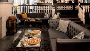 Una sala de estar moderna con un sofá, una mesa de comedor con pizza y una zona de bar al fondo.