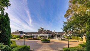 A large building with a central courtyard, surrounded by well-maintained hedges and trees.