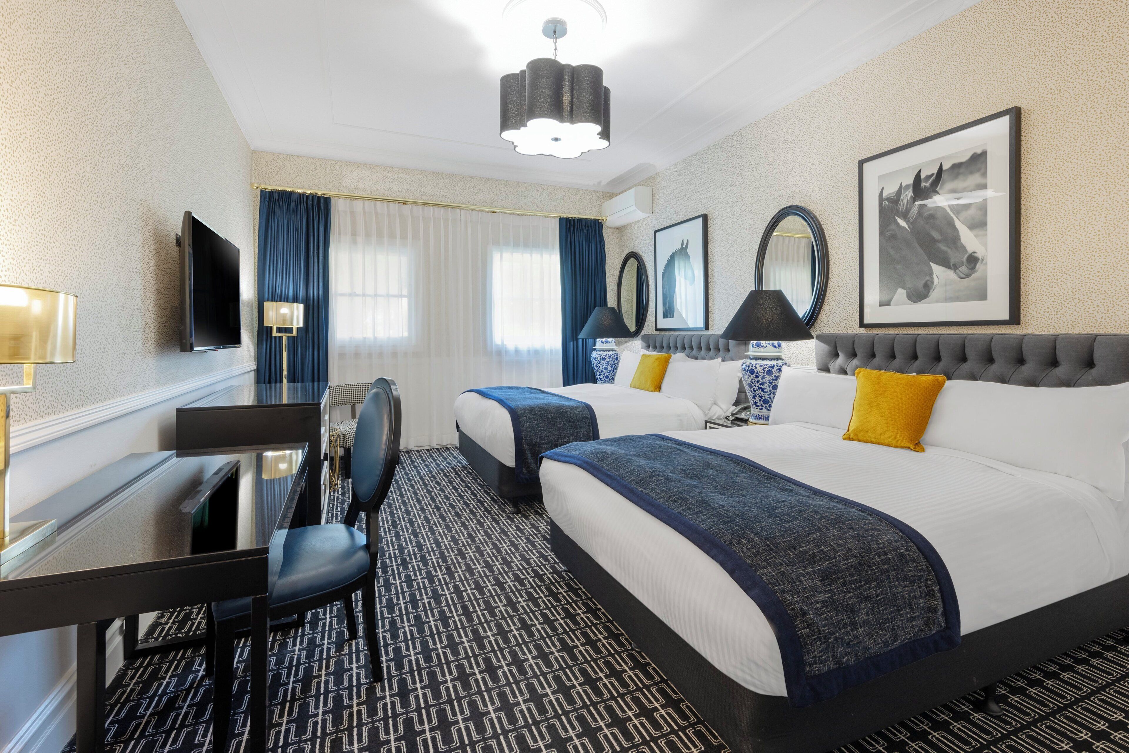 A hotel room with two beds, a desk, and a chair.