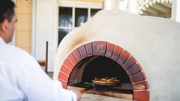 Une personne utilise un four à pizza doté d’un intérieur en briques et d’une cheminée.