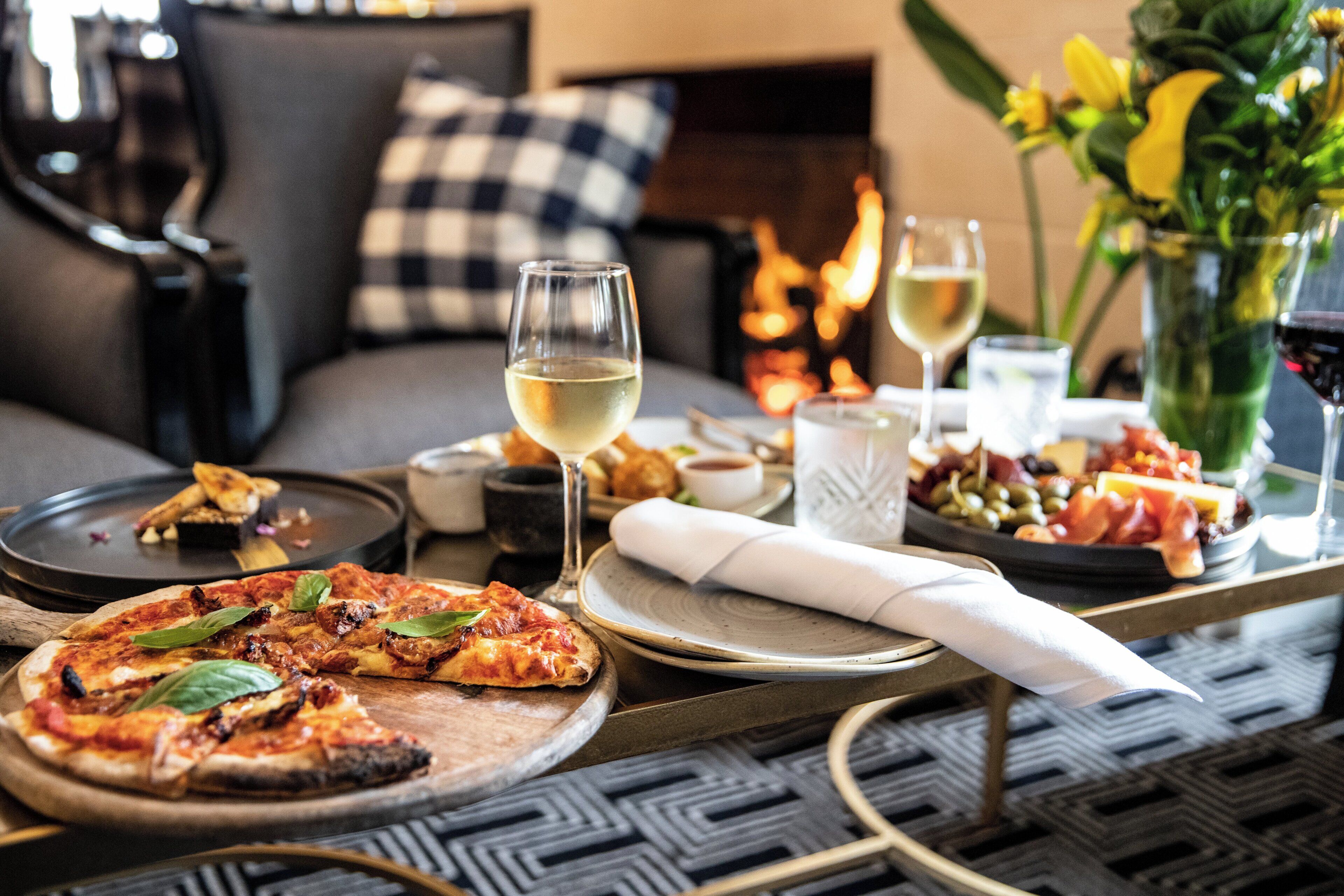 A dining table with pizza, wine glasses, and a vase of flowers.