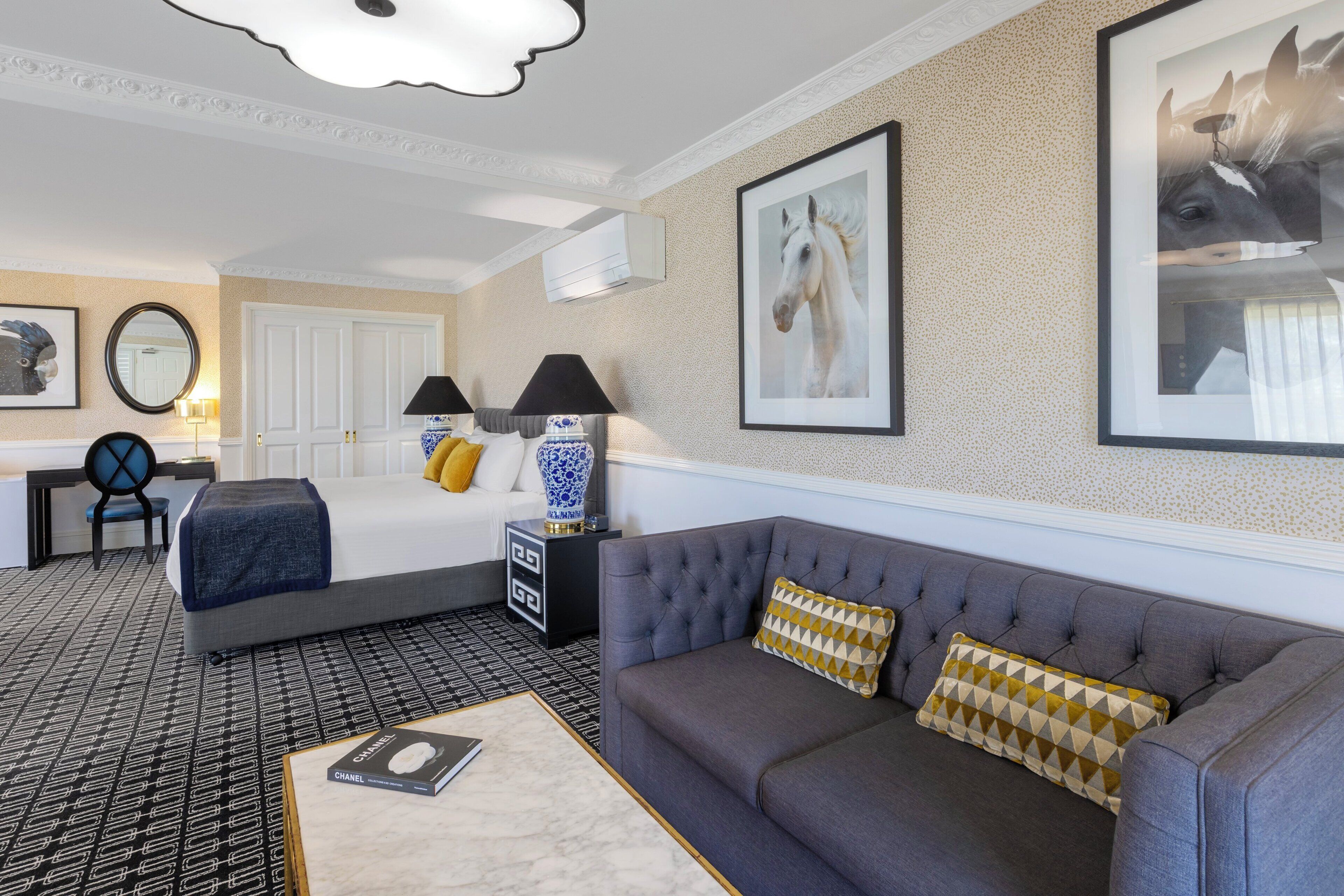 A hotel room with a bed, a sofa, a desk, and a chair.