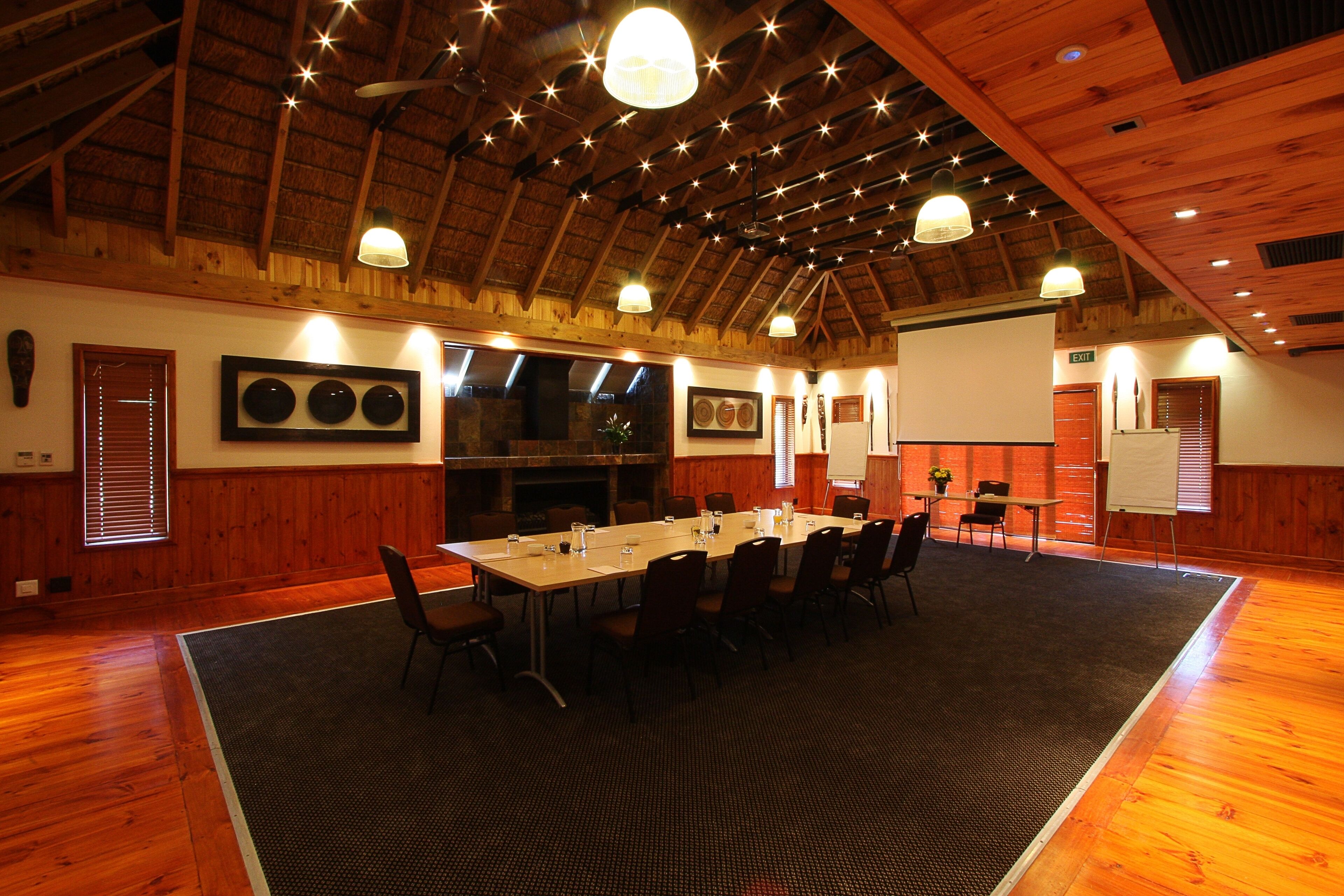 A conference room with a long table, chairs, and a projector screen.