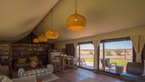 A cozy interior with wicker pendant lights, a bar area, and a view of the outdoors. - Tau Game Lodge (Ramotshere Moiloa)