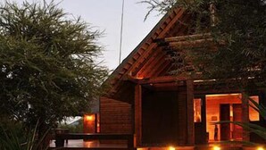 A wooden cabin with a porch and steps leading to a door. - Tau Game Lodge (Ramotshere Moiloa)
