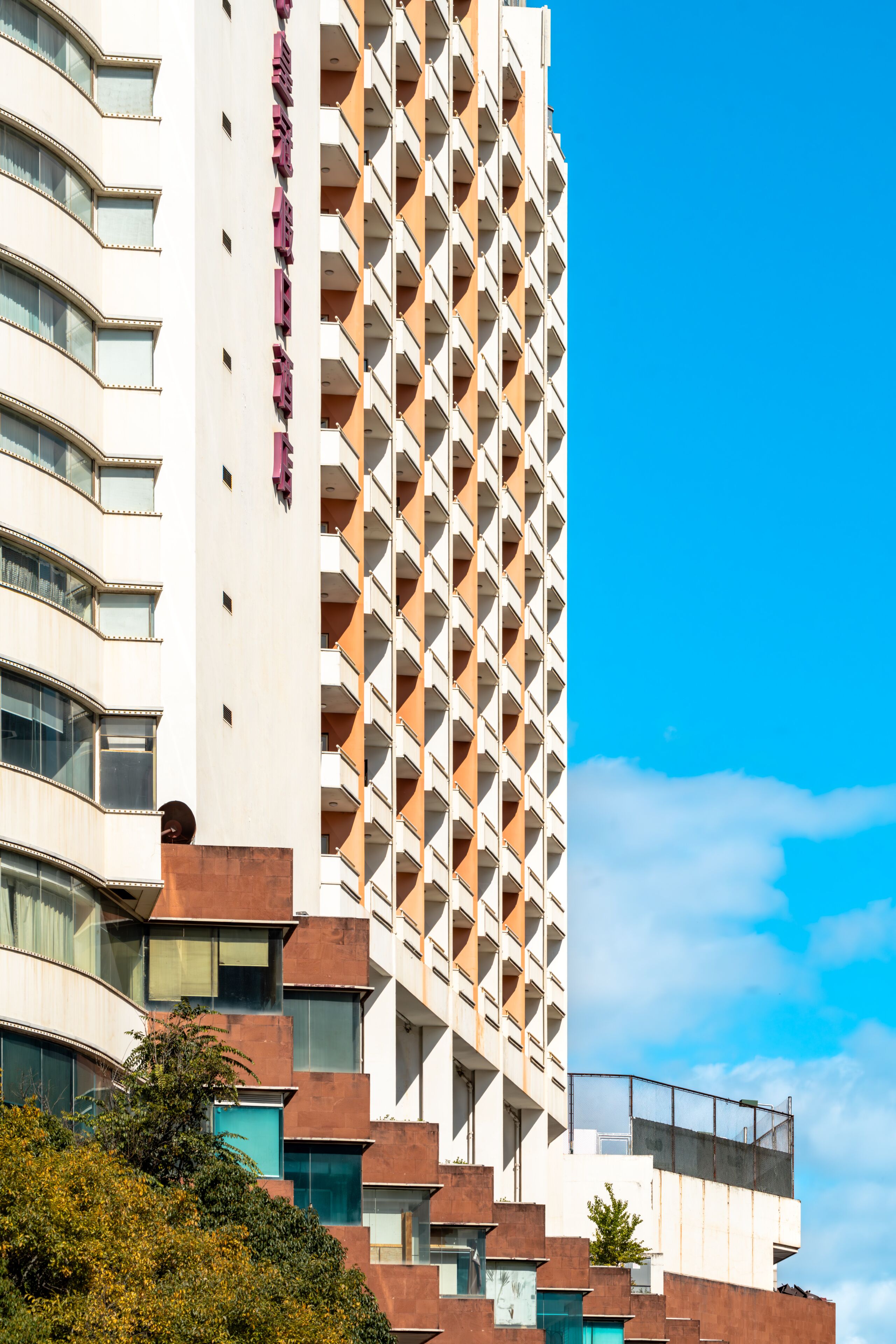 Un hôtel à plusieurs étages, doté d’une façade géométrique remarquable, de balcons et surplombant un ciel d’un bleu éclatant.