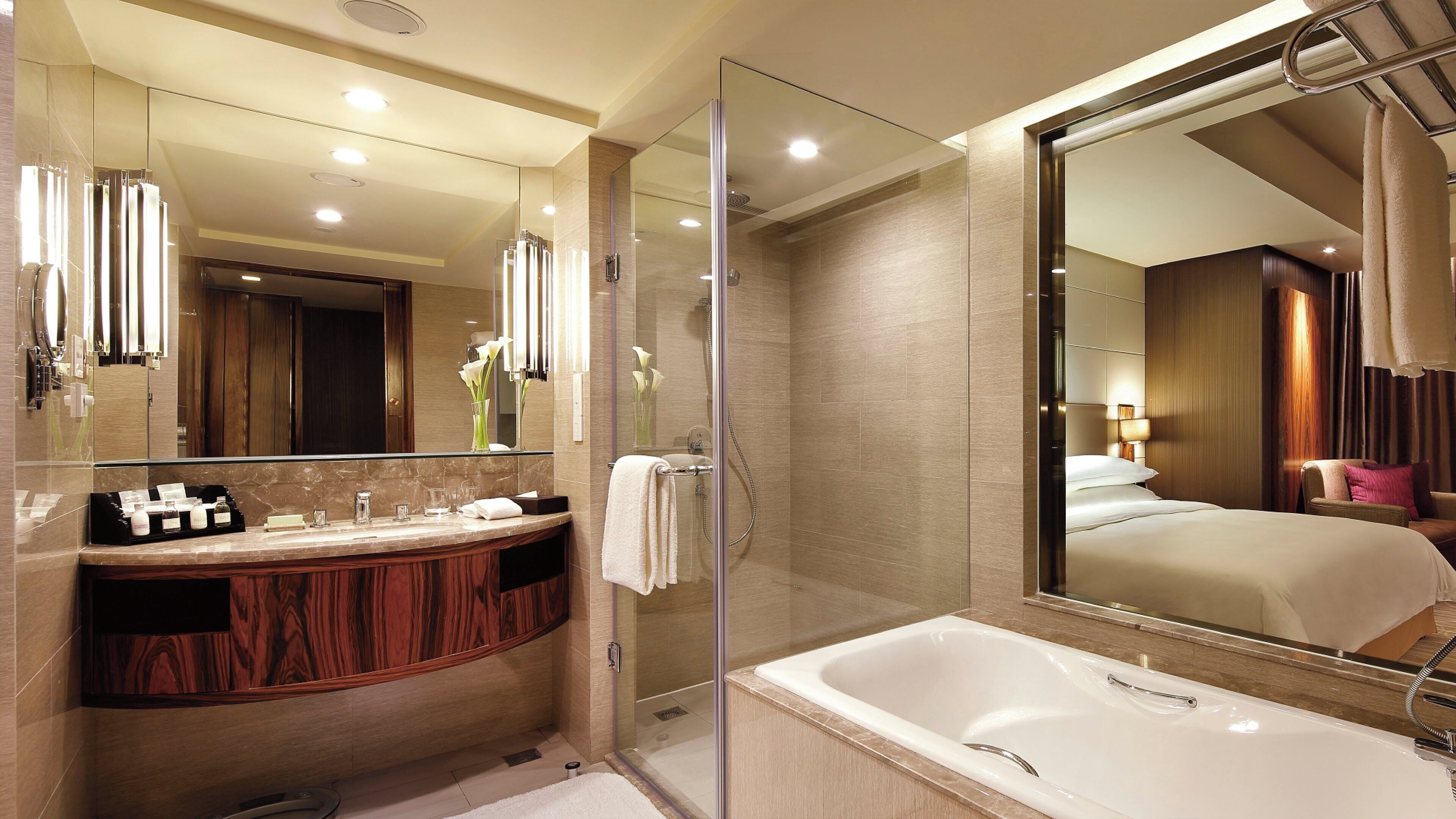 Un baño moderno con ducha de vidrio, un espejo grande y una bañera.