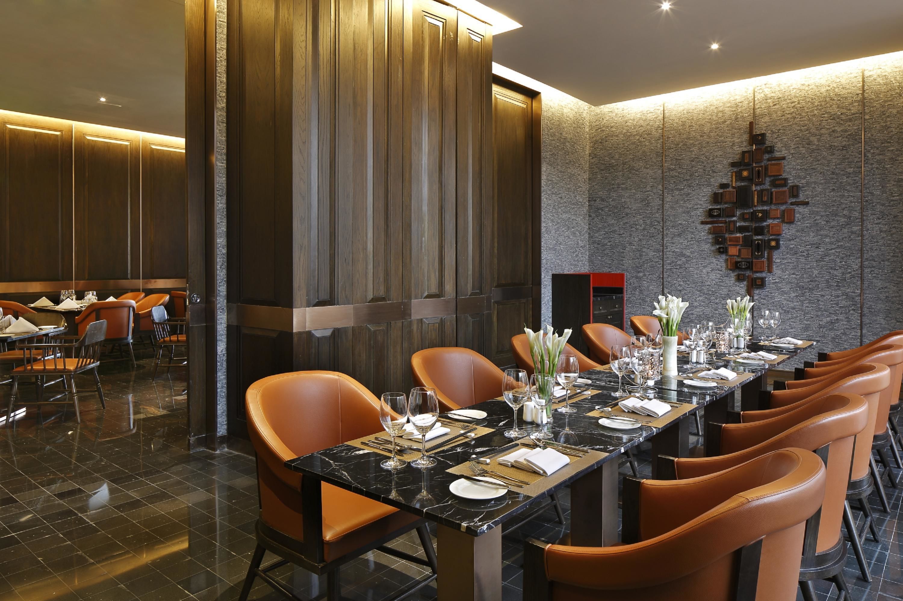 Una larga mesa de comedor dispuesta con sillas, una chimenea y un elemento decorativo en la pared.