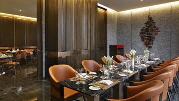 Una larga mesa de comedor dispuesta con sillas, una chimenea y un elemento decorativo en la pared.