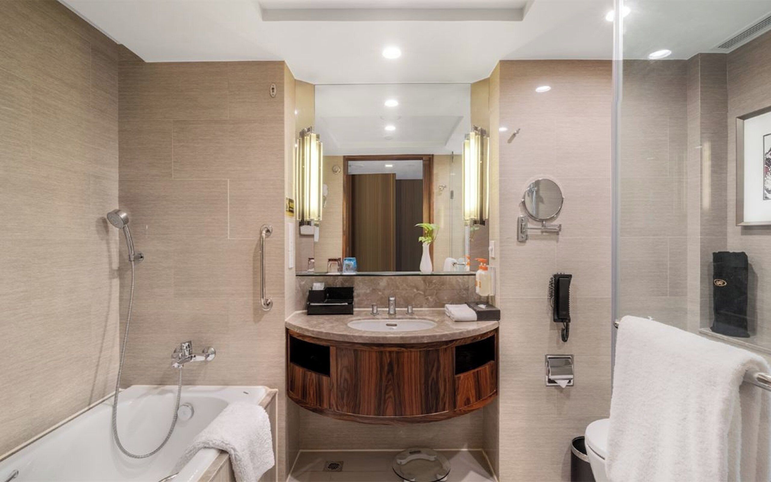A modern bathroom with a bathtub, a shower, a vanity with a sink, and a mirror.