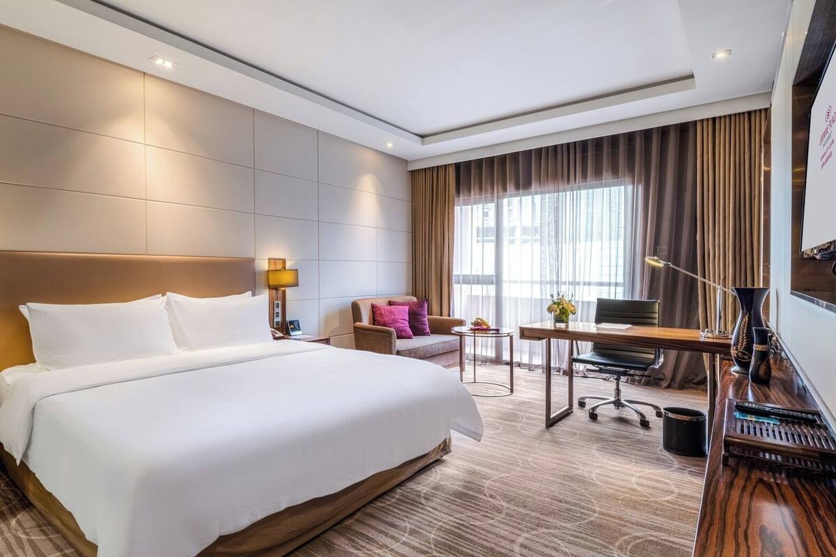 Una habitación de hotel con una cama grande, un escritorio, una silla y una mesita.
