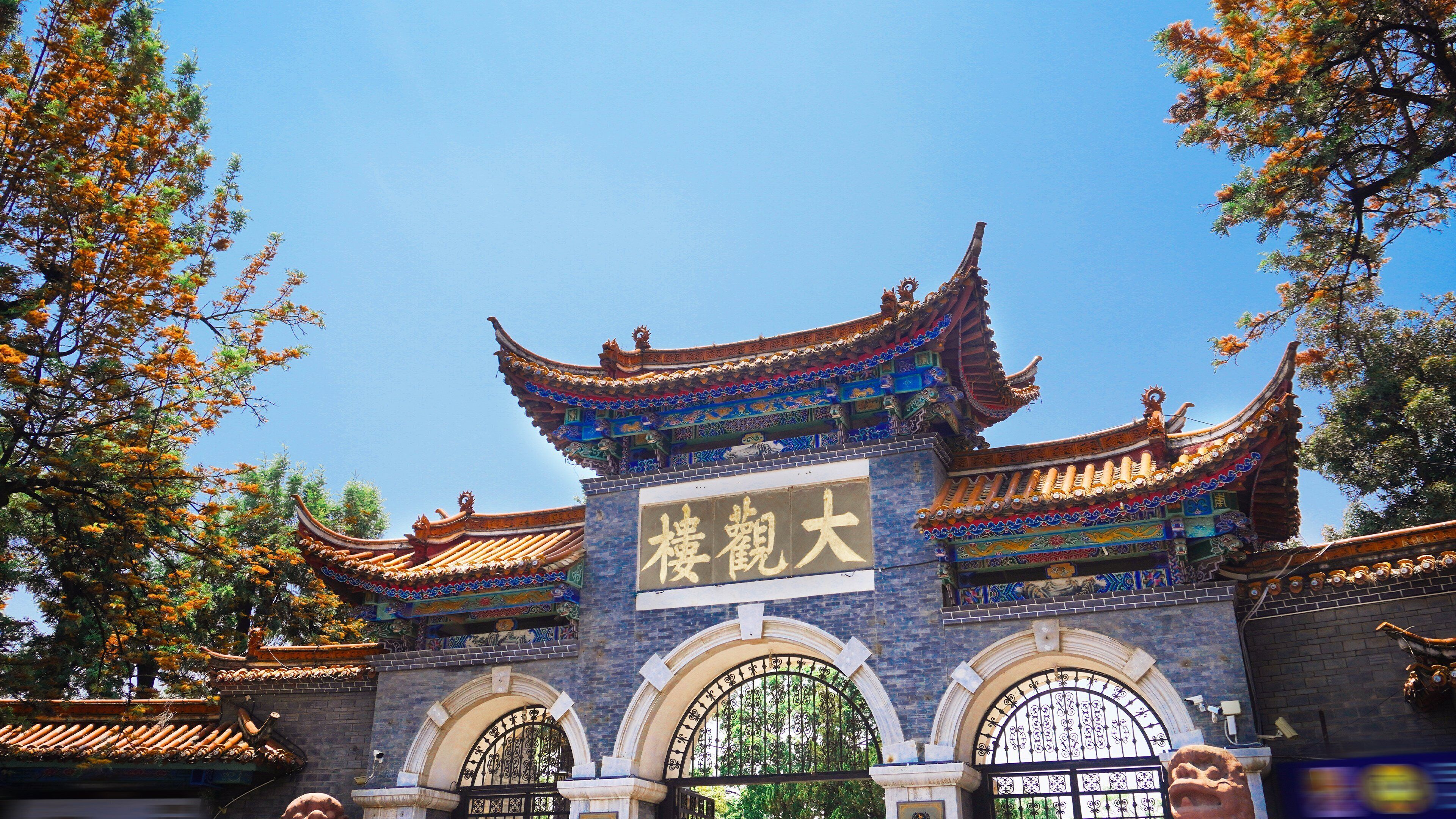 A traditional Chinese gate with ornate architecture and a clear blue sky in the background.