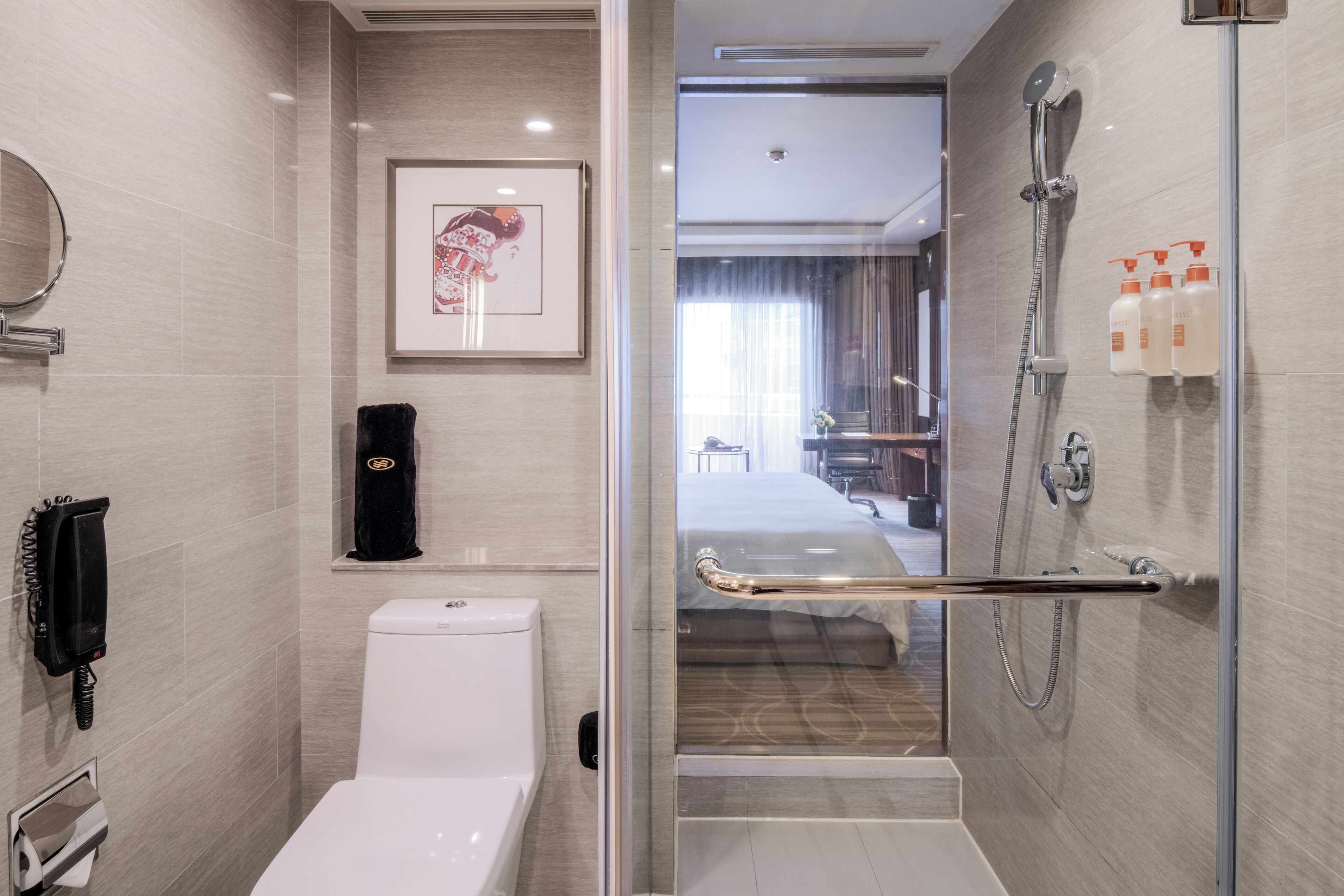A modern bathroom with a toilet, a shower, and a glass door leading to a bedroom.
